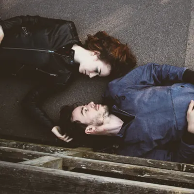 couple laying on the ground while the woman rubs the man's head in loving support